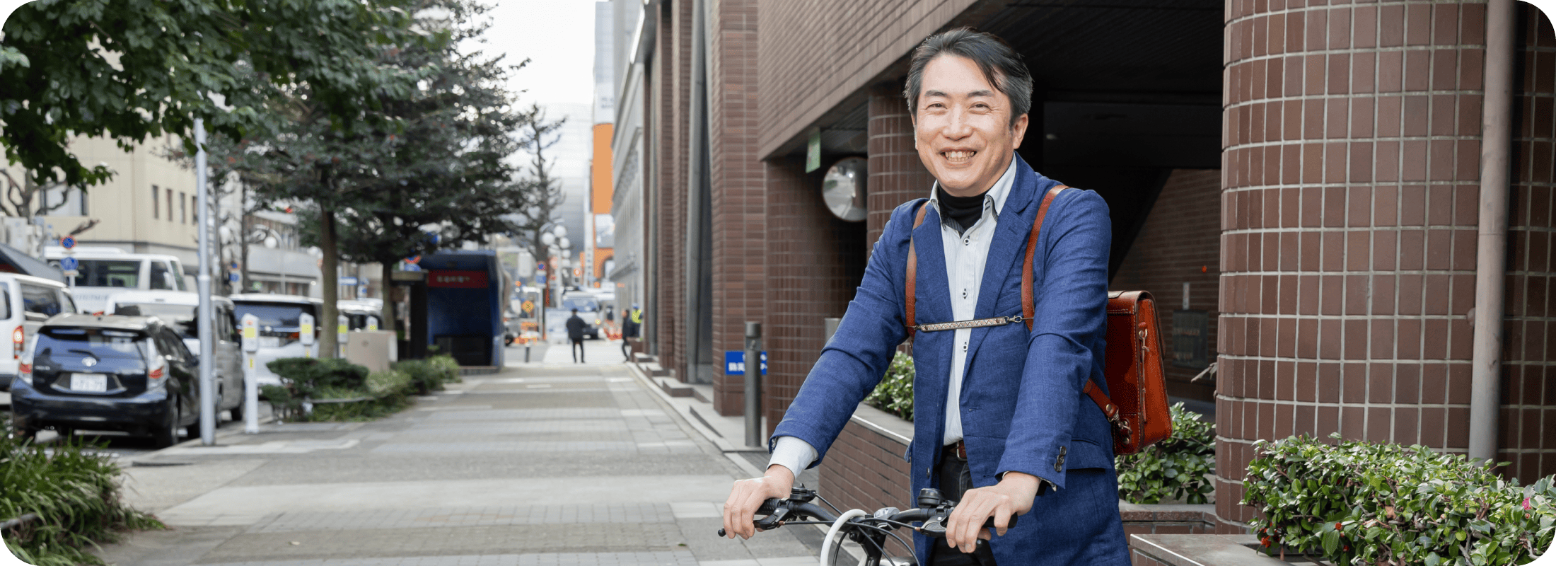 社長が笑顔で自転車の横に立っているシーン